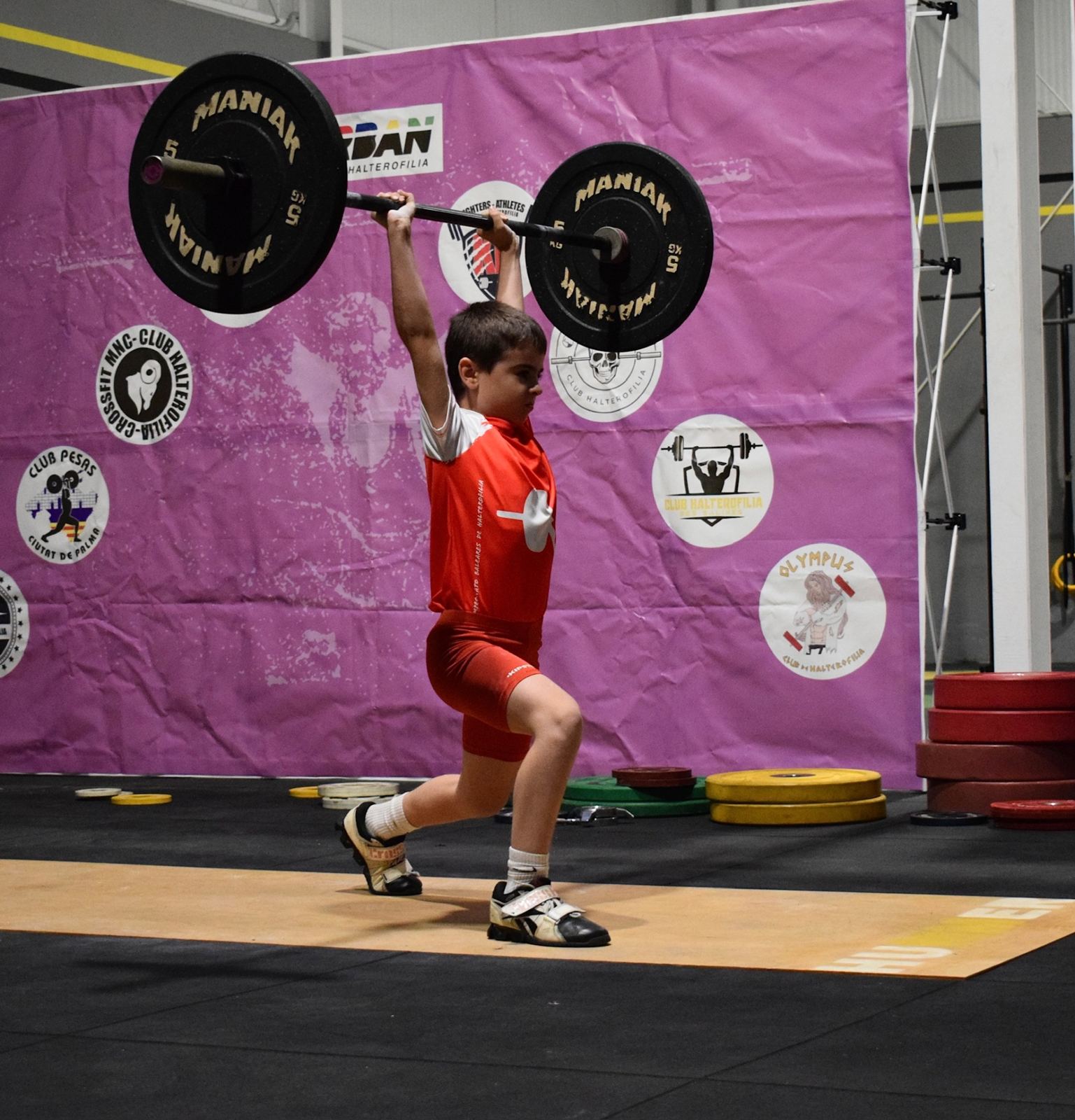 Joven atleta de la cantera ejecutando un jerk en competición